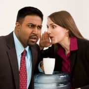 business man and business woman whispering gossip at water cooler